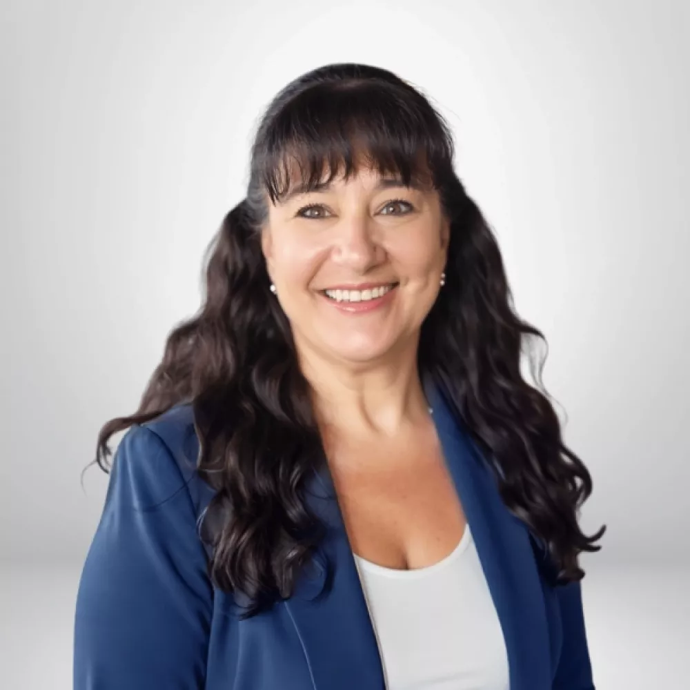 Sonia Carey in a blue blazer with long dark hair against a light gray background.