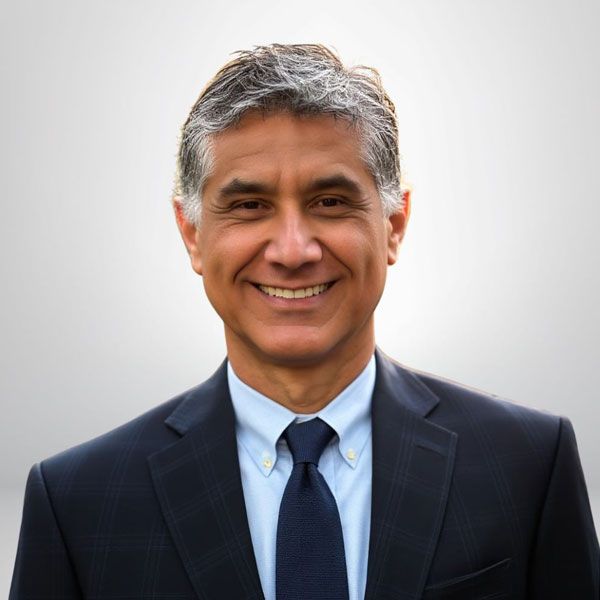 Smiling man in a suit and tie against a neutral background.