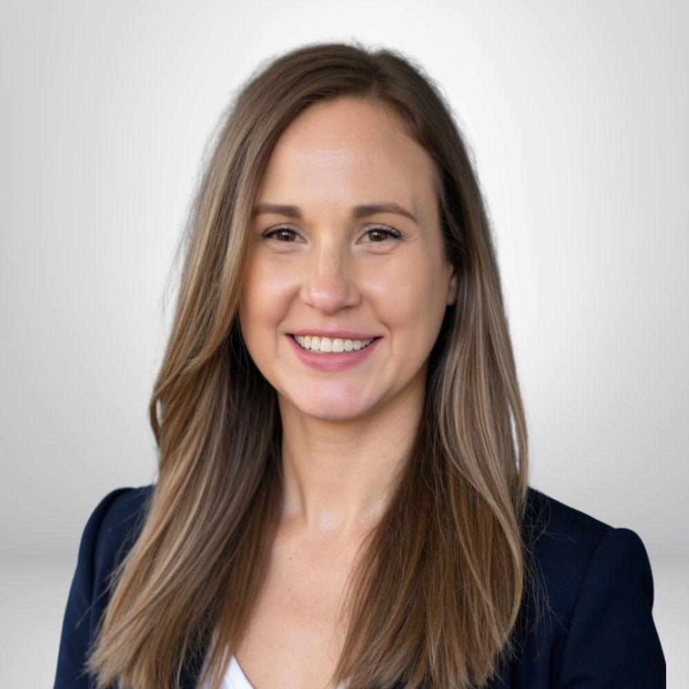 Smiling professional woman with long hair, wearing a blue blazer, against a plain background.
