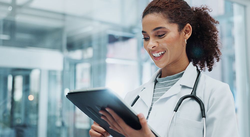 Smiling doctor using a digital tablet in a modern hospital, enhancing healthcare with technology.