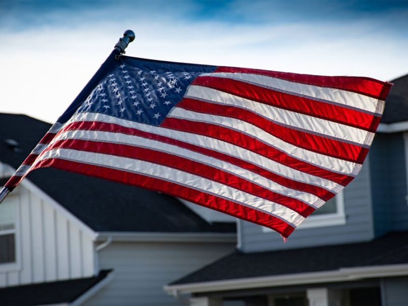 USA flag waving outside a suburban home on a clear day.