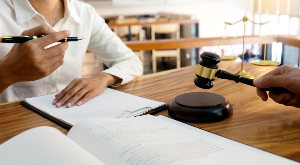 Legal consultation with gavel, scales, and papers on a desk in a professional office setting.