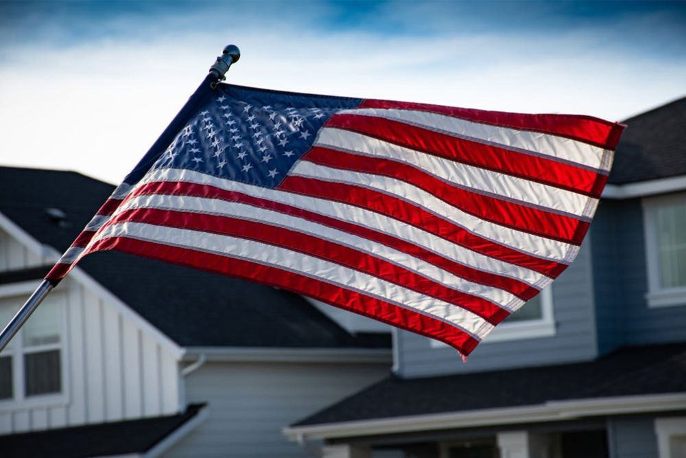 USA flag waving outside a suburban home on a clear day.
