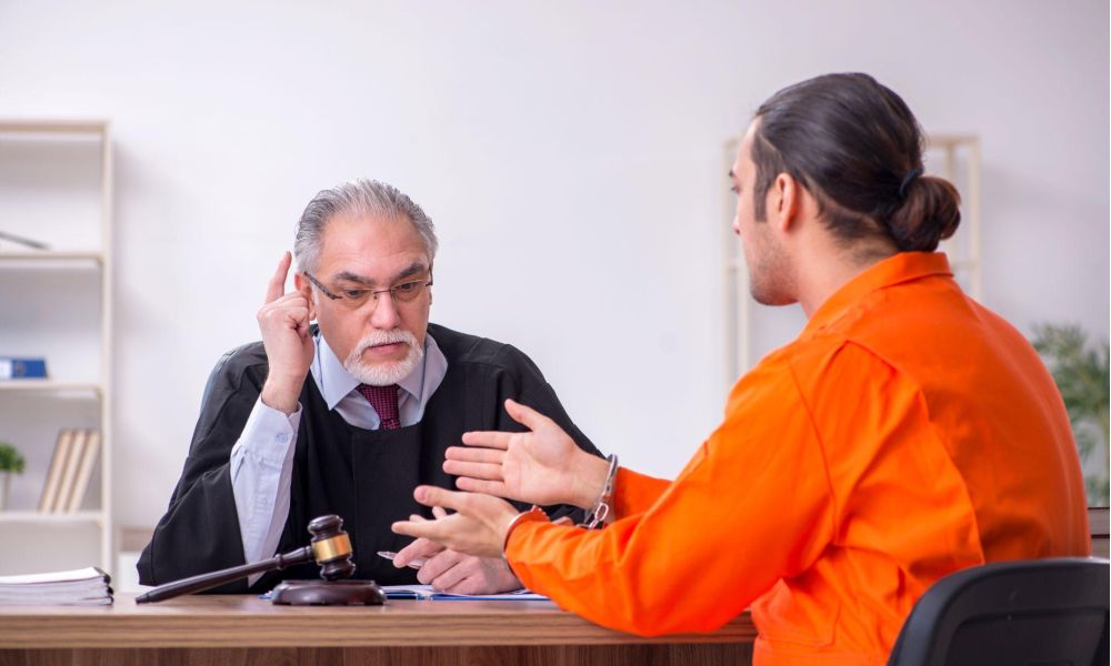 Judge listening to a prisoner in an orange jumpsuit during a courtroom discussion.