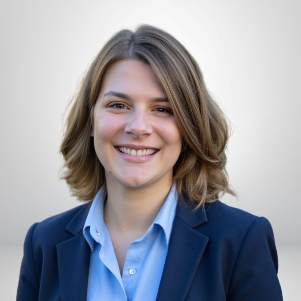 Smiling woman in blue blazer and shirt, light background, close-up professional portrait.