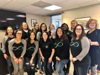 Group of people smiling in a room, wearing matching shirts, gathered for a team event.