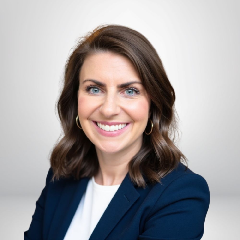 Smiling woman in a blue blazer against a light background, professional headshot.