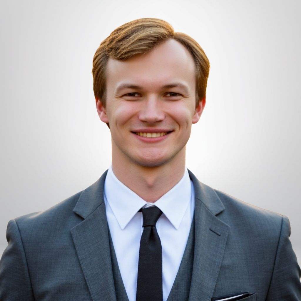 Smiling man in a grey suit and black tie, professional portrait against neutral background.