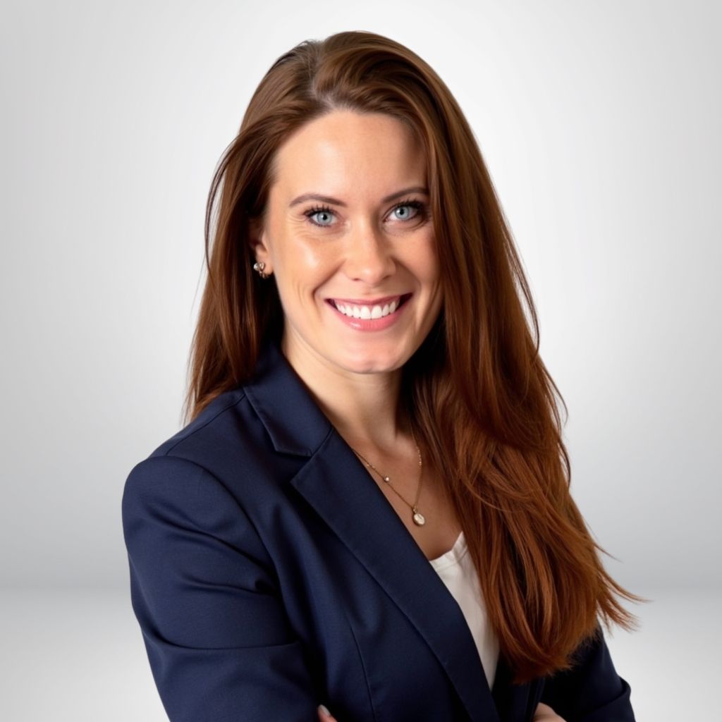 Smiling woman in a navy blazer with long brown hair, confident and professional studio portrait.