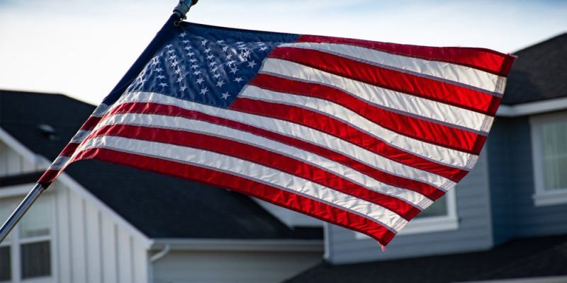 USA flag waving outside a suburban home on a clear day.