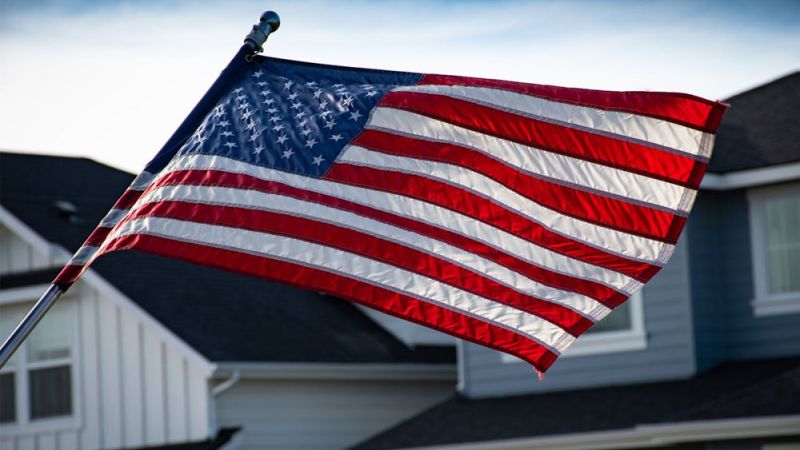 USA flag waving outside a suburban home on a clear day.