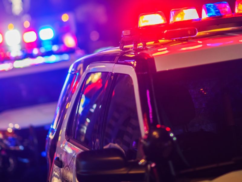 Police cars with flashing lights at night, showing emergency response in urban setting.