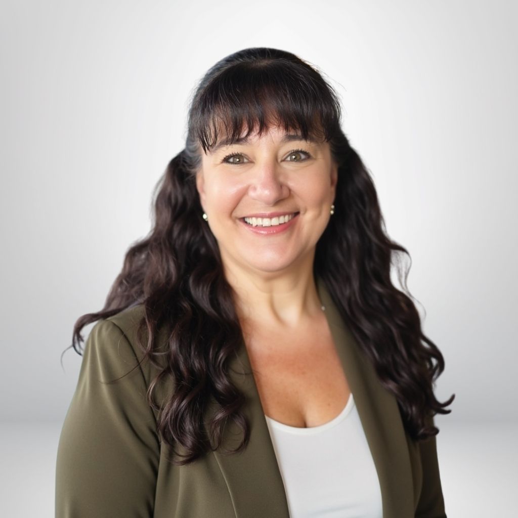 Smiling woman with long dark hair in a blazer, white shirt, against a neutral background.