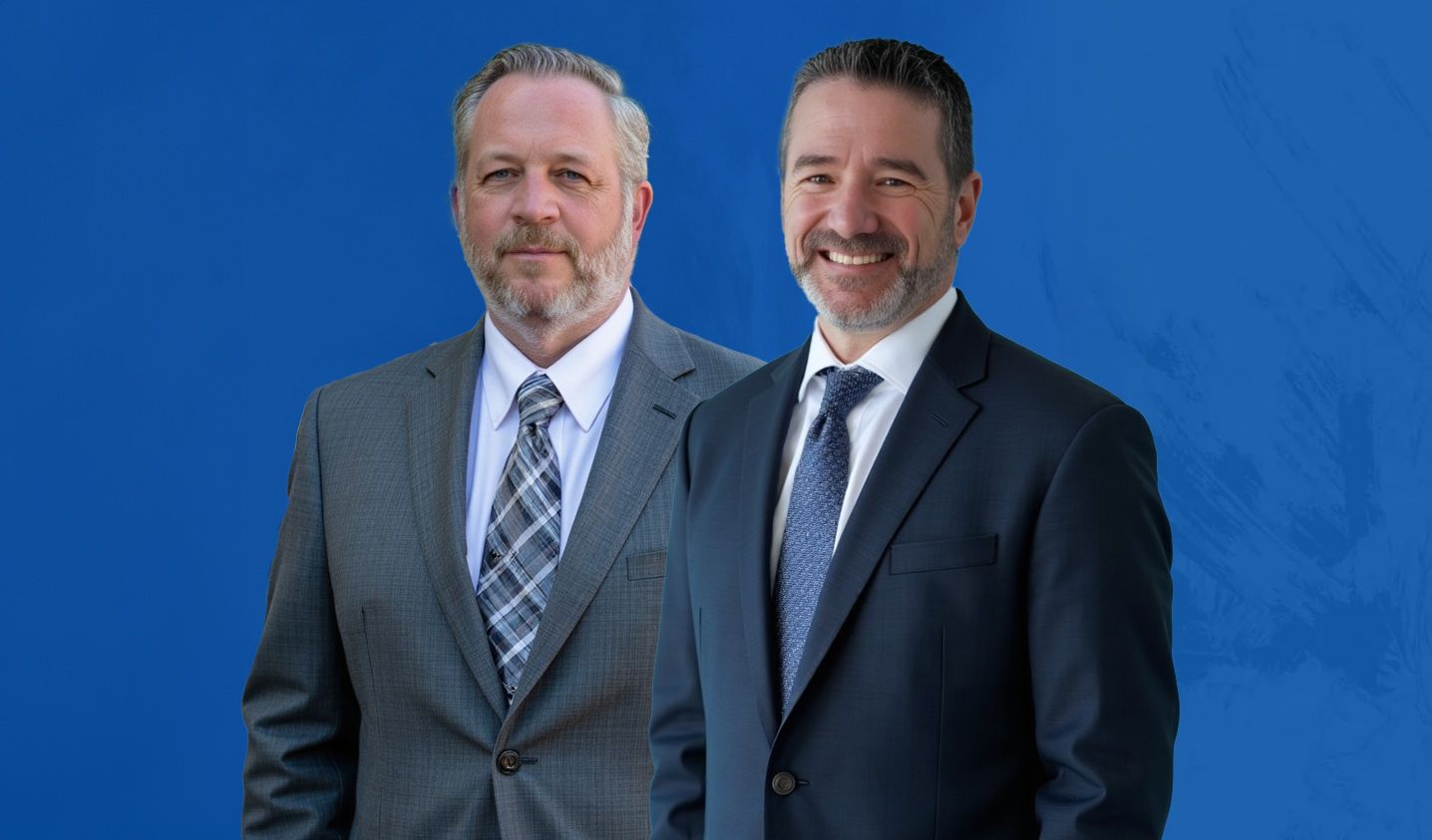 Two businessmen in suits smiling against a blue background.