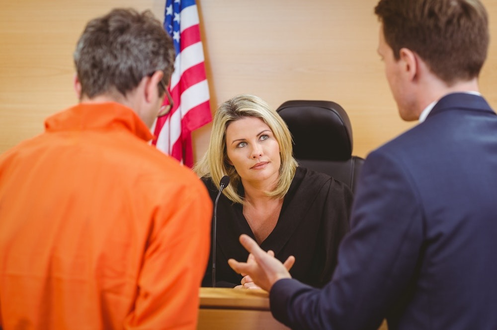 Judge Attentively Listening to Lawyers in a Courtroom Discussion with the American Flag in the Background