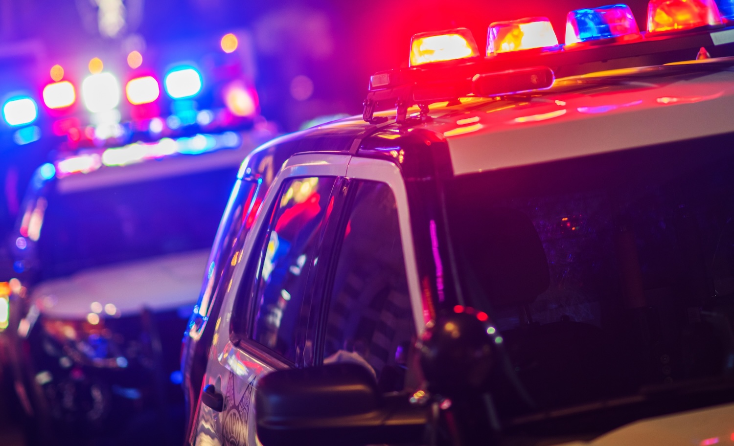 Police cars with flashing lights at night, showing emergency response in urban setting.