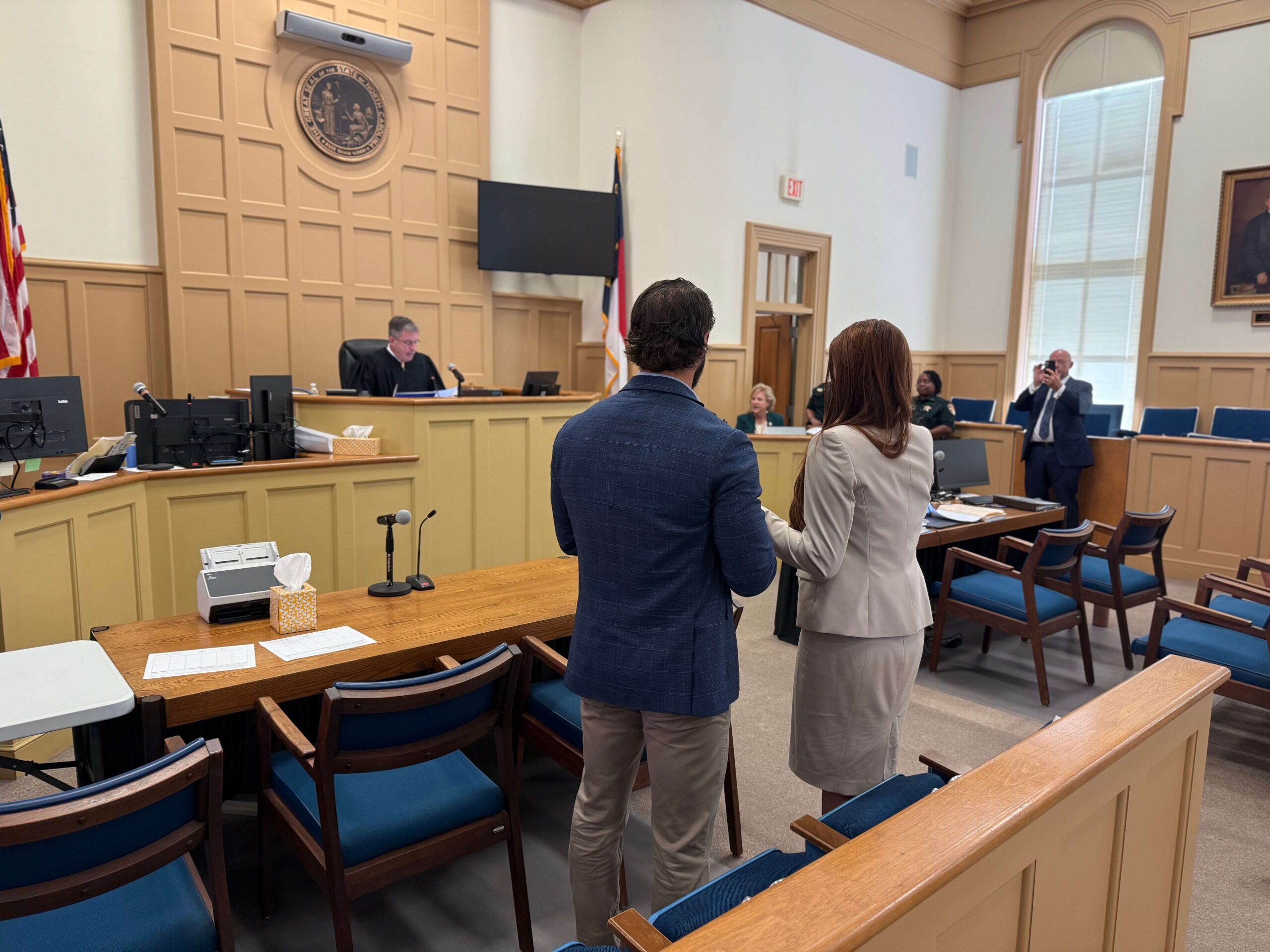 Two People Standing in a Courtroom Facing a Judge During a Legal Proceeding