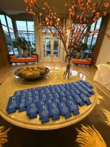Elegant Lobby Display with Branded Blue Koozies on Table Floral Centerpiece and Stylish Seating Arrangement