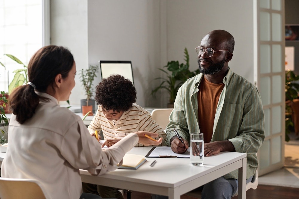 Family Discussing Homework at a Table with Plants Focusing on a Young Child's learning.
